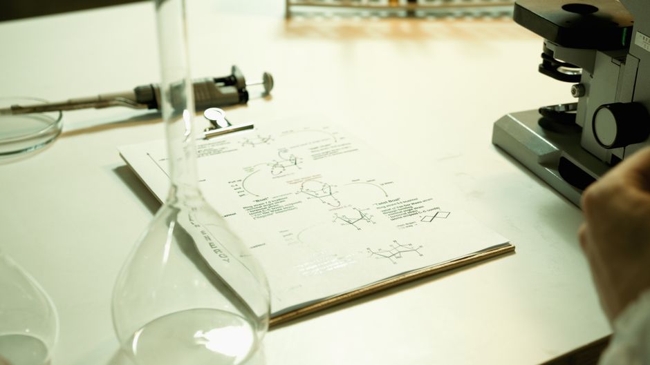 Close-up of a laboratory setup with documents, beaker, and microscope on a table.
